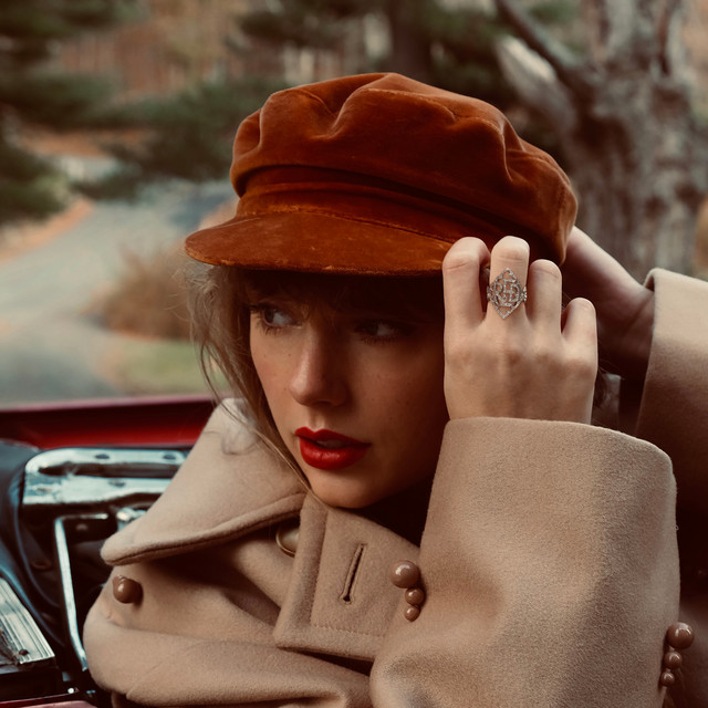 Taylor Swift's cover of the album Red. It is a blond woman in a tan coat and a red hat